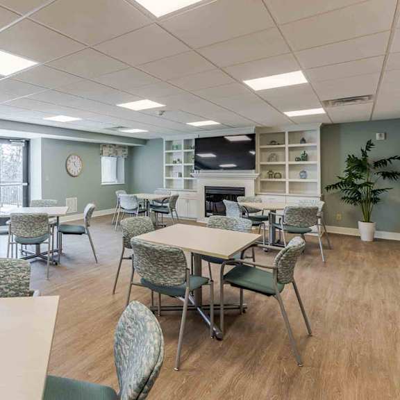 a room with tables and chairs and a clock on the wall.