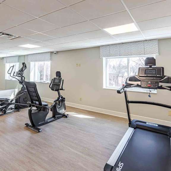a gym with treadmills, stationary bikes, and elliptical machines.