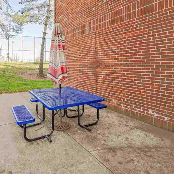a blue picnic table is set up outside next to a brick wall.