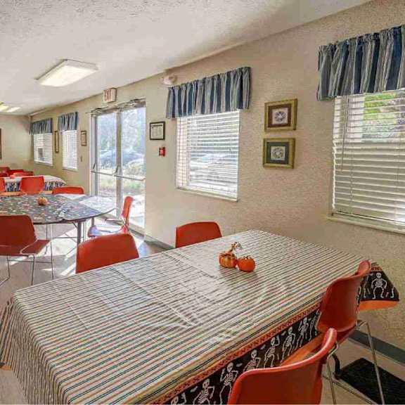 a dining room with a striped tablecloth and red chairs.