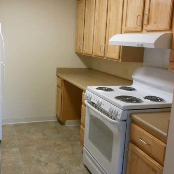 a kitchen with a white refrigerator, white stove, and wooden cabinets.