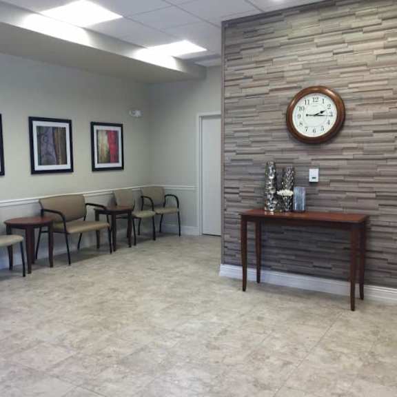 a waiting room with a clock on the wall and chairs and a table.