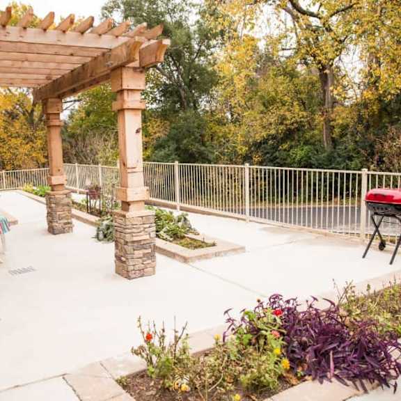a patio with a table and chairs under a wooden pergola.