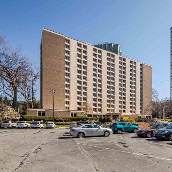 a parking lot with cars and two buildings in the background.