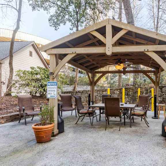 a wooden gazebo with a sign that says "bar" is surrounded by chairs and tables.