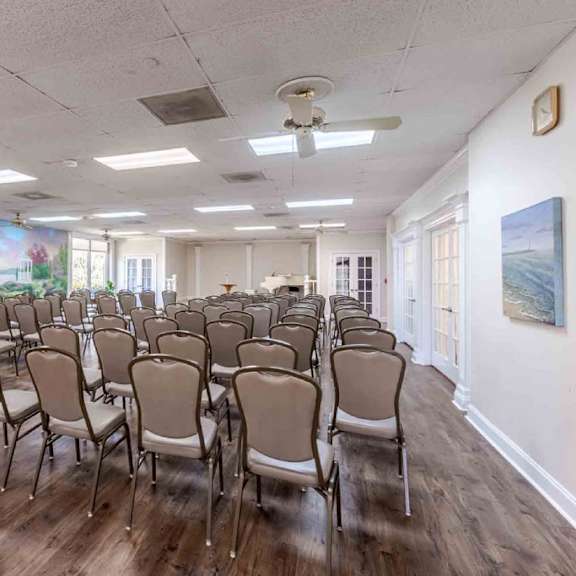 a room with a long table and chairs and a painting on the wall.