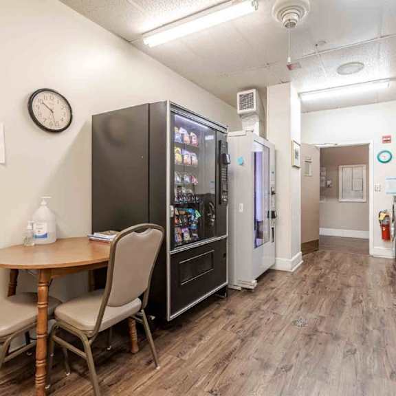 a laundry room with a washer and dryer, a table and chairs, and a clock on the wall.