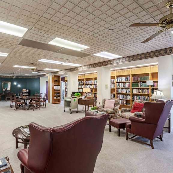 a room with a ceiling fan and bookshelves filled with books.