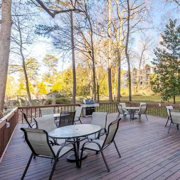 a wooden deck with a table and chairs surrounded by trees.