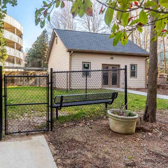 a small house with a black fence and a bench in front of it.