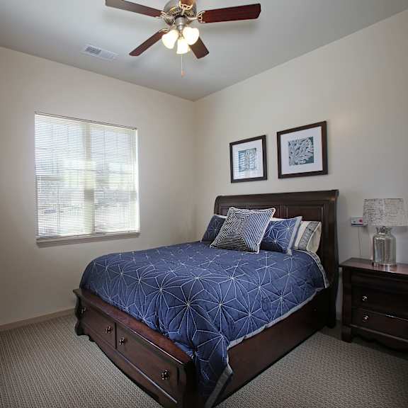 a bedroom with a bed, nightstands, and a ceiling fan.