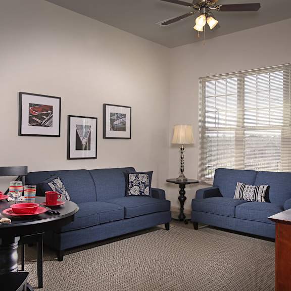 a living room with a blue couch, a black table, and a ceiling fan.