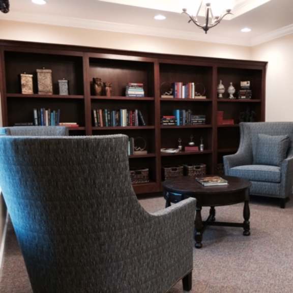 a living room with a grey chair, a grey armchair, and a brown coffee table.