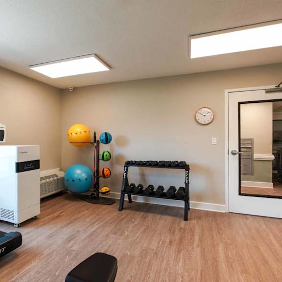 a room with a treadmill, a bench, and a clock on the wall.