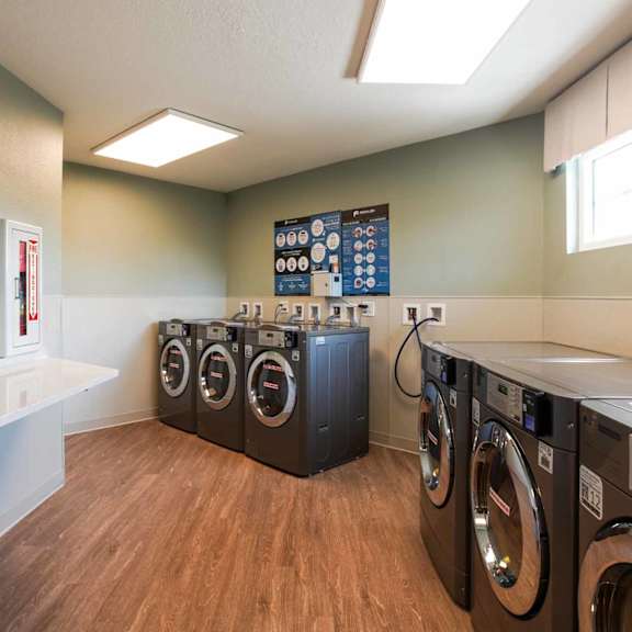 a laundry room with a row of washers and dryers.