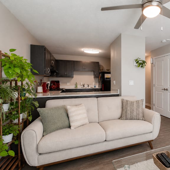 a living room with a beige couch and a ceiling fan.