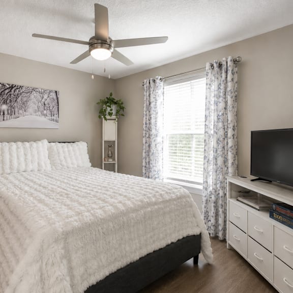 a bedroom with a large bed, a ceiling fan, and a television.