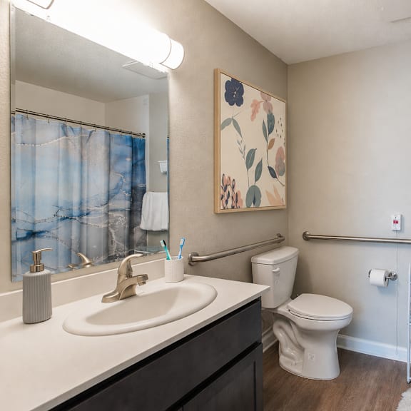 a bathroom with a toilet, sink, and a painting on the wall.