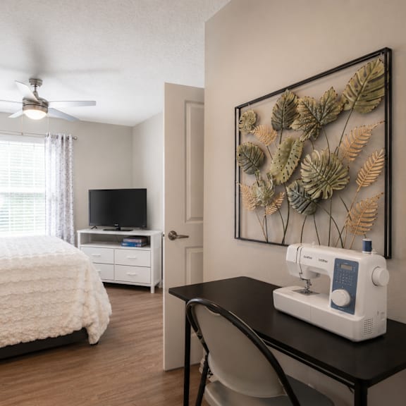 a sewing machine is on a table in a room with a bed and a television.