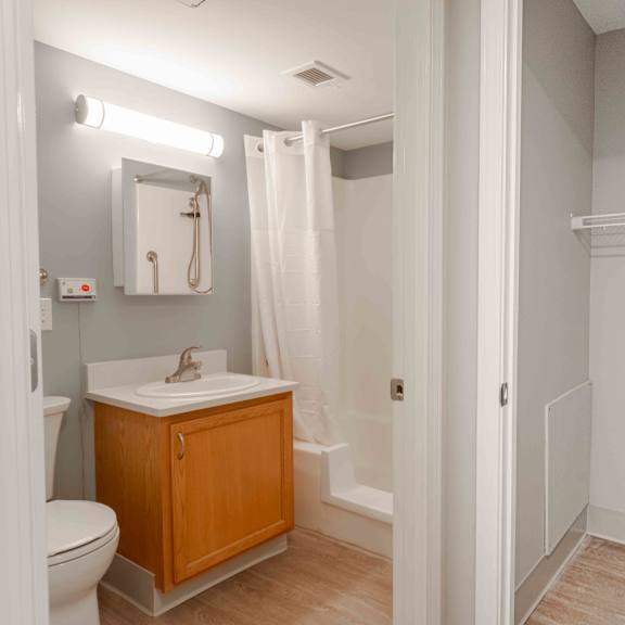a bathroom with brand new toilet, sink, and a mirror. to the right is the large hall closet.