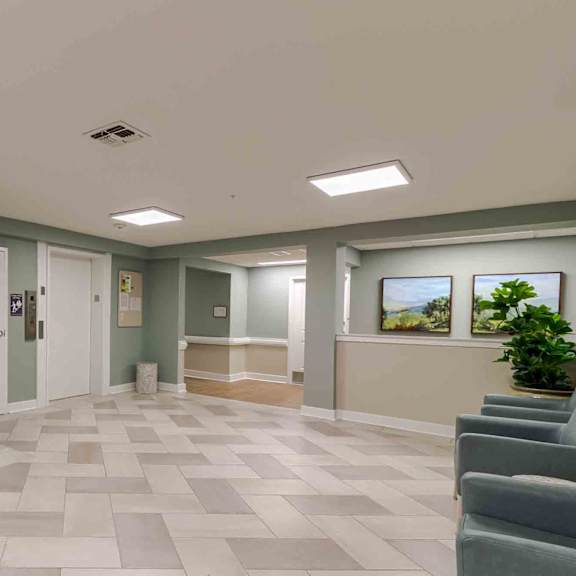 a hallway with a tiled floor and a trash can on the left.