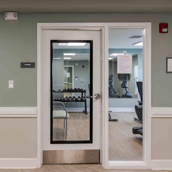 a gym room with a mirrored door and a painting on the wall.