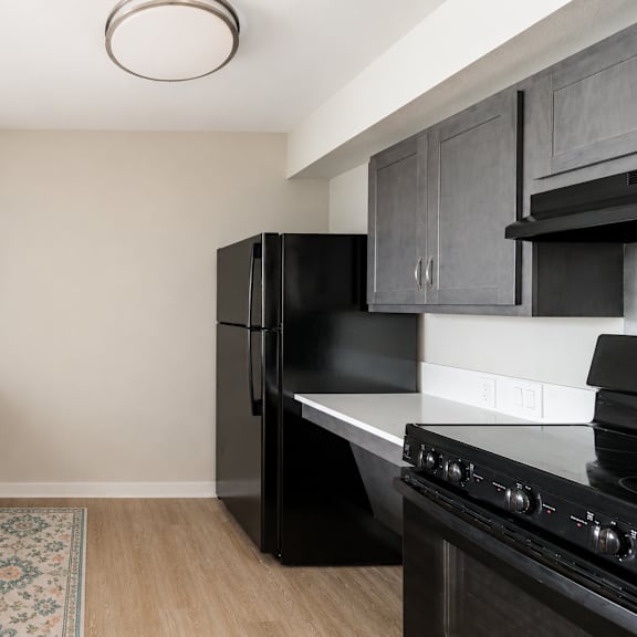 a kitchen with black appliances and wooden floors.