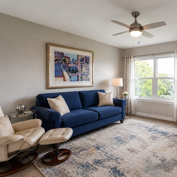 a living room with a blue couch and a fan.