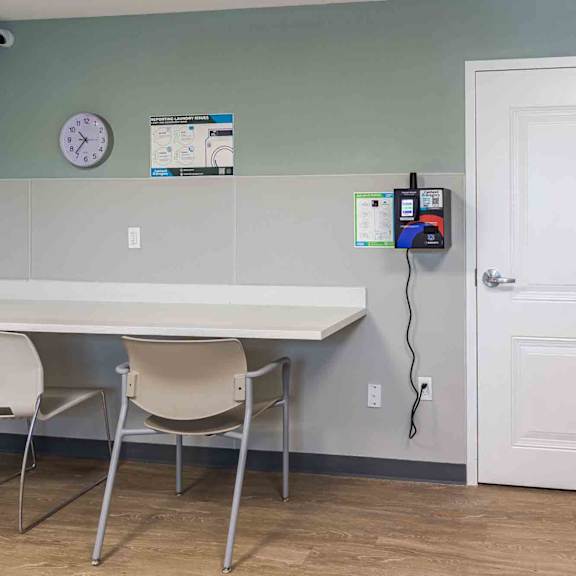 a white table with two chairs in a room with a clock on the wall.