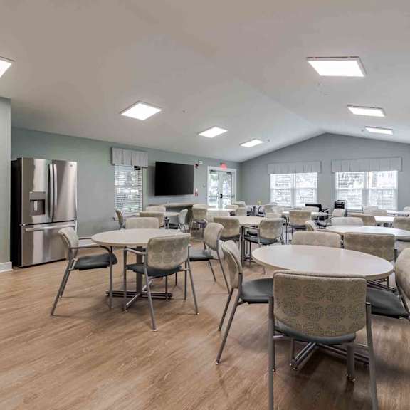 a spacious room with tables and chairs and a television.