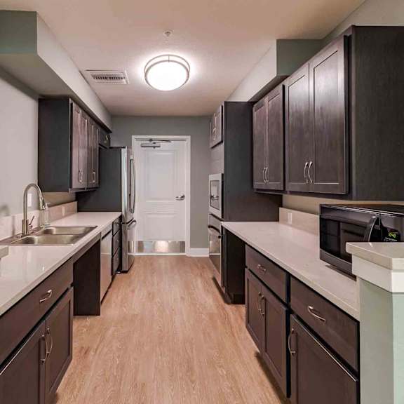 a kitchen with dark brown cabinets and light wood floors.