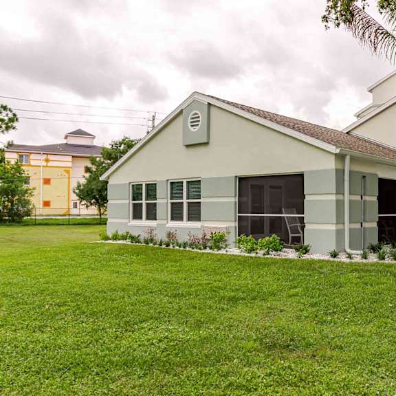 a white building with a brown roof is surrounded by a green lawn.