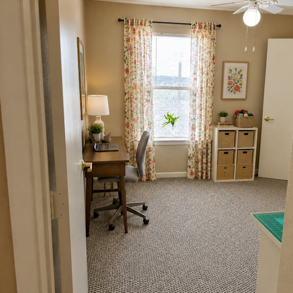 a room with a desk, chair, and a window with curtains.