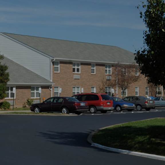a large building with a grey roof is surrounded by a parking lot.