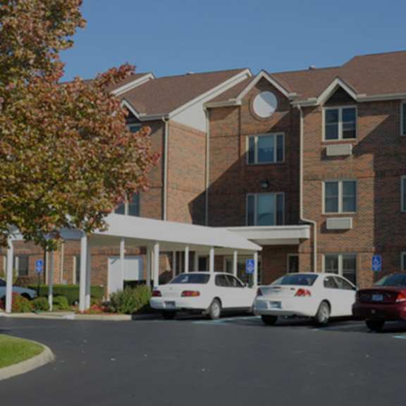 a parking lot in front of a brick building with three cars parked.