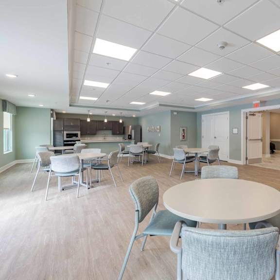 a room with tables and chairs and a kitchen area.