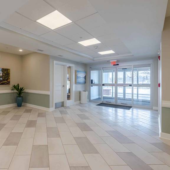 a long hallway with a tile floor and white pillars.