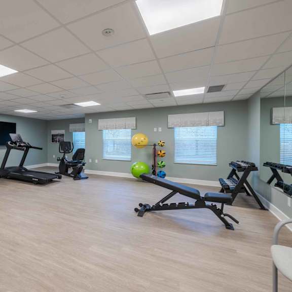 a spacious gym with a variety of exercise equipment and a clock on the wall.