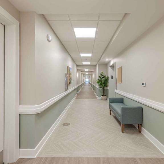 a long hallway with a bench and a plant.