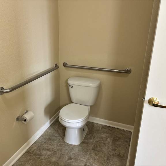 a white toilet with a towel rack and a towel hanging on the wall.