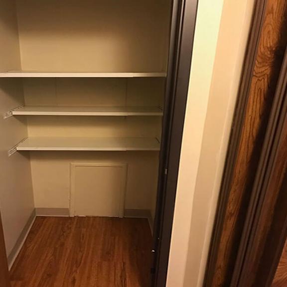 a small, empty closet with a white door and wooden floor.