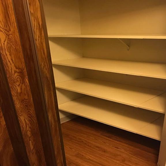 empty white shelves in a room with wooden floors and white walls.