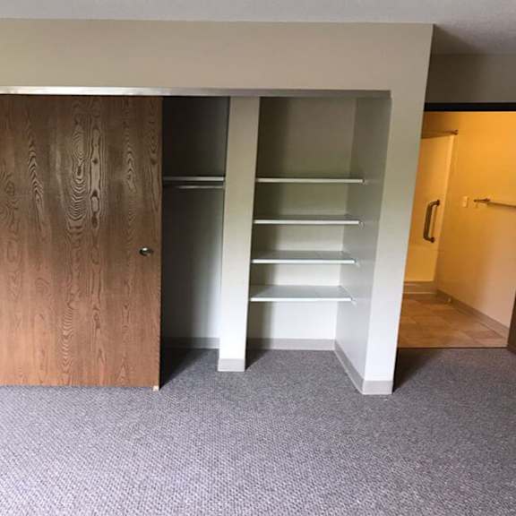 a room with a wooden door and a white shelving unit.