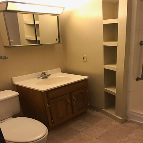 a bathroom with a toilet, sink, and a shower.
