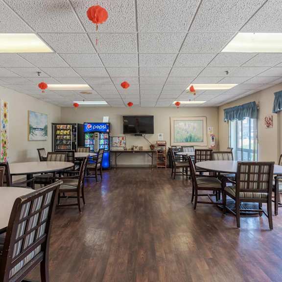 a room with wooden floors and tables and chairs.
