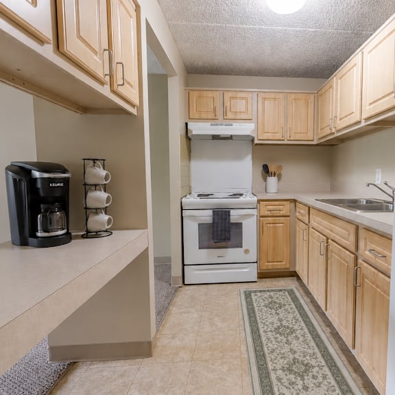 a kitchen with a white fridge, white oven, and wooden cabinets.