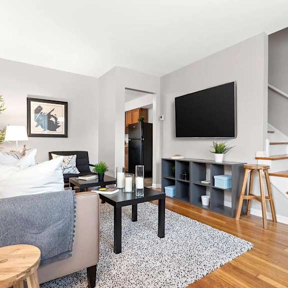 a living room with a couch and a tv and a staircase