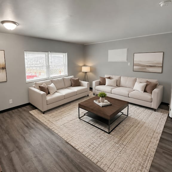a living room with a white couch, a coffee table, and a plant.