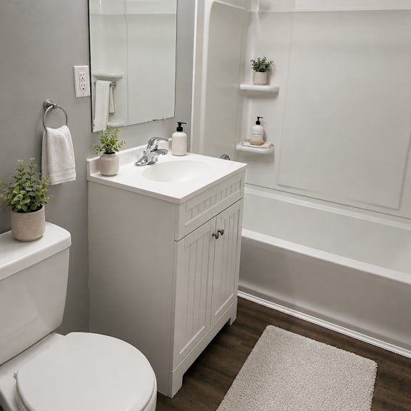 a white bathroom with a toilet, sink, and mirror.