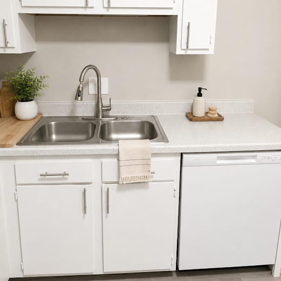 a kitchen with white cabinets and a stainless steel sink.
